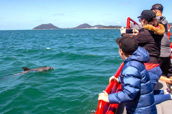 a group of people riding on the back of a boat in the water